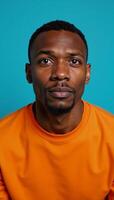 Portrait of puzzled African American man in orange top set against vibrant blue backdrop photo