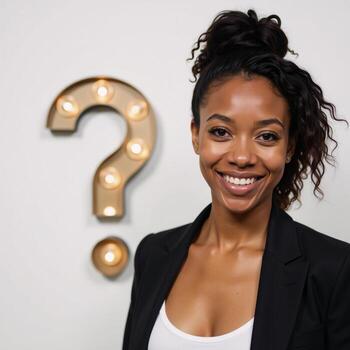 Smiling African American Coco posed inquisitively with a lightbulb beside her against a clean white backdrop photo