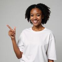 A youthful Black woman smiles in a white tee and points on light gray backdrop perfect mockup for ad designs photo