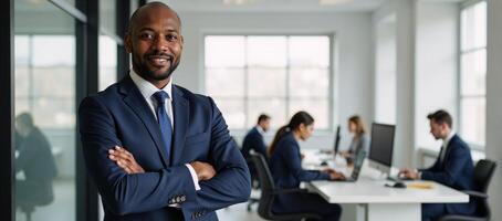 A confident African American businessman poses assertively within a bustling modern tech office photo
