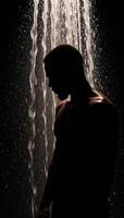 A cooling shower scene featuring a black AfricanAmerican man in silhouette with refreshing water pouring over him photo