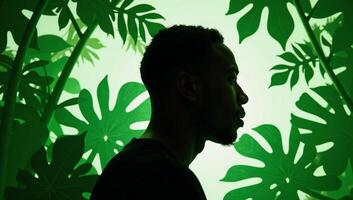 AfricanAmerican man profile with tropical plants in papercut style showcasing an interplay between human and nature rendered primarily in shades of green photo