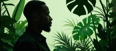 AfricanAmerican man profile with tropical plants in papercut style showcasing an interplay between human and nature rendered primarily in shades of green photo