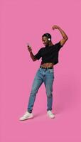 A lively generation Z AfricanAmerican man stands alone grooving to his favorite online tunes through headphones and a mobile device photo