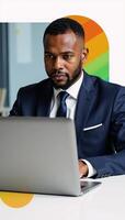 Office setting featuring an AfricanAmerican businessman working on his laptop surrounded by vibrant graphics photo