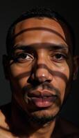 Closeup portrait of an African American man showcasing shadowy facial details and distinct striped patterns across his visage photo