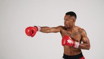 A powerful AfricanAmerican boxer with a painted body throws a punch using red boxing gloves photo
