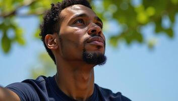 An introspective AfricanAmerican collegian contemplates under a clear sky photo