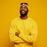 Optimistic Black Man in yellow beanie sweatshirt points upward against bright yellow backdrop Advertising wallpaper mockup featuring African American male photo