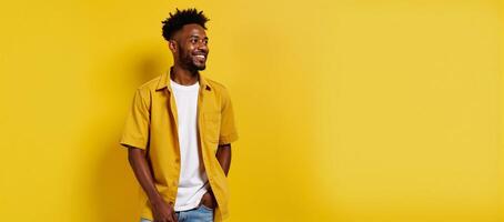 A cool stylish Gen Z black hipster stands on a bright yellow backdrop gazing off into ad space with a happy expression photo