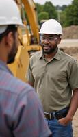 Two African American workers conversing on site one with hard hat and safety glasses other blurred in the foreground photo