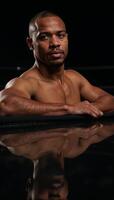 Muscular African American boxer with sweaty forehead leaning on left elbow and covering eyes with right hand photo