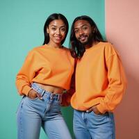AfricanAmerican couple wearing baggy orange sweatshirts and denim pants pose against a pastel background photo