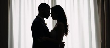 African American couple embracing silhouetted against empty backdrop with heart symbol and word love photo