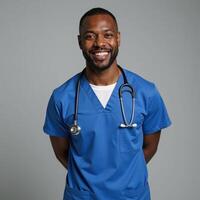 A friendly confident AfricanAmerican male nurse stands tall smiling warmly while wearing blue scrubs and a stethoscope exuding care and compassion in his expression photo