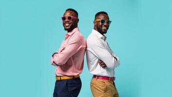 Cheerful African American duo pose confidently backtoback against a bright blue backdrop showcasing stylish summer outfits with eyecatching sunglasses photo