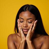 African American woman with closed eyes touchingly portrait on yellow backdrop with natural makeup photo