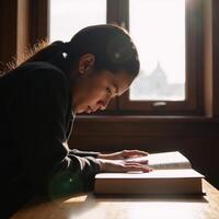 A sunlit college library scene Closeup of deep concentration on an African American student with a book seated in a cozy corner photo