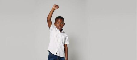 A confident AfricanAmerican boy stands proudly against an expressive backdrop fist raised photo