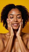African American woman with closed eyes touchingly portrait on yellow backdrop with natural makeup photo