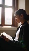 A sunlit college library scene Closeup of deep concentration on an African American student with a book seated in a cozy corner photo