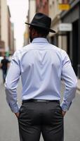 African American man in stylish hat stands with back to camera on city street photo
