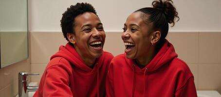 Young AfricanAmerican couple in matching red hoodies share a joyful laugh in a bathroom photo