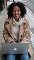 African American woman sitting outdoors with laptop curly hair winter attire shallow DoF cinematic daylighting photo