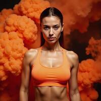 Woman in orange sports bra set against an orange smoky background photo