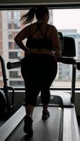 Obese woman jogging on a treadmill silhouette photo