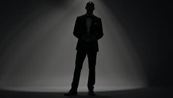 AfricanAmerican man silhouetted against a light background while wearing a tuxedo photo