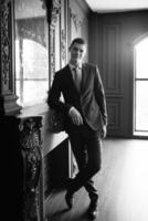 portrait of groom in blue three piece suit with tie on wedding day photo