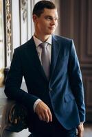 portrait of groom in blue three piece suit with tie on wedding day photo
