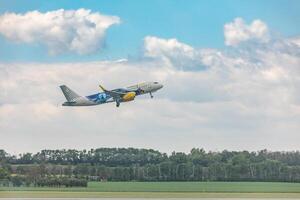 A large airplane flying over a field of green trees photo