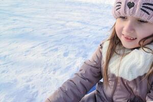 A girl enjoys sledding on a snowy day while wearing a warm hat and coat, copy space. photo