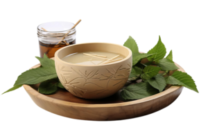 A bowl of liquid with a wooden spoon and a jar of honey. The bowl is on a wooden tray with leaves on it png