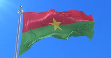 Flag of Burkina Faso waving at wind in slow with blue sky, loop video