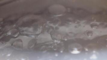 Close-up of boiling water bubbles in dish. Bubbling clean water in saucepan for cooking. Boiling water in kettle video