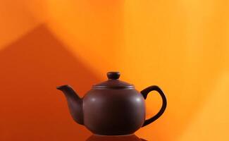 teapot from clay on an orange background with geometric pattern photo