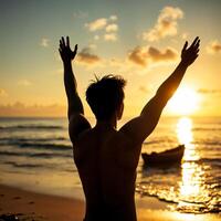 A man is standing on the beach with his arms raised photo
