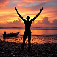 A man is standing on a beach with his arms raised photo