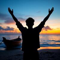 A man is standing on the beach with his arms raised photo