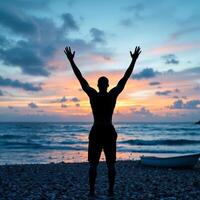 A man is standing on a beach with his arms raised in the air photo