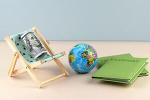 Chaise lounge with dollars and globe on a light background. photo