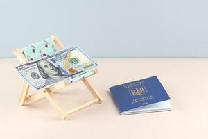 Ukraine passport and chaise lounge with dollars and globe on a light background. photo