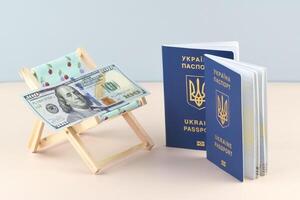 Ukraine passport and chaise lounge with dollars and globe on a light background. photo