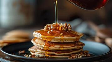 stack of pancakes drizzled with maple syrup and topped with pecans. photo