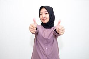 portrait of Indonesian Asian woman wearing shirt and hijab showing ok sign with one hand on eyes looking at camera through fingers. giving sign of agreement. Isolated on white Background photo