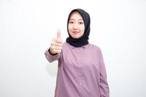 portrait of Indonesian Asian woman wearing shirt and hijab showing ok sign with one hand on eyes looking at camera through fingers. giving sign of agreement. Isolated on white Background photo
