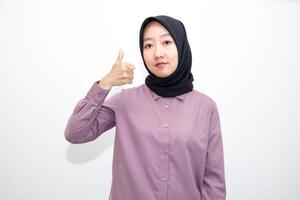 portrait of Indonesian Asian woman wearing shirt and hijab showing ok sign with one hand on eyes looking at camera through fingers. giving sign of agreement. Isolated on white Background photo
